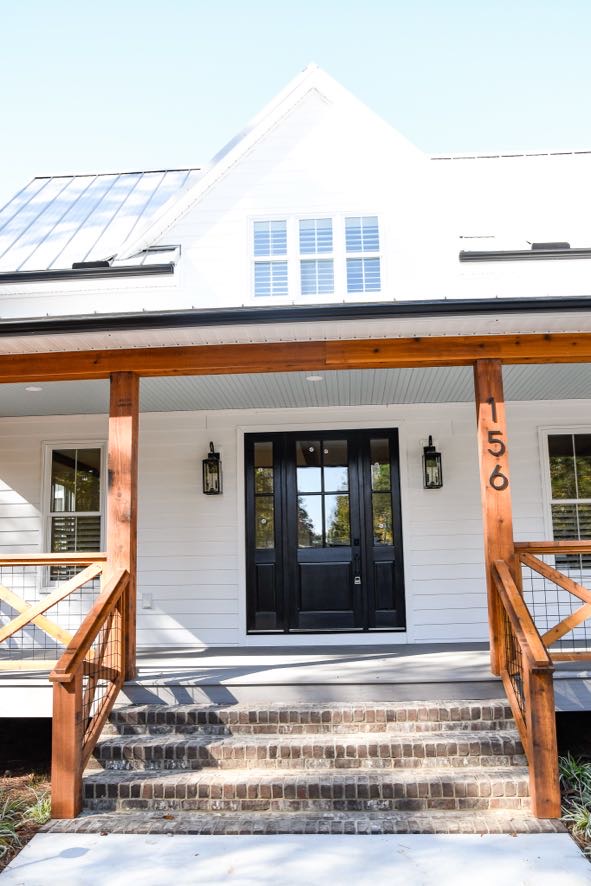 Custom coastal farmhouse exterior with white siding and wood accents built by Ryan Noble Construction