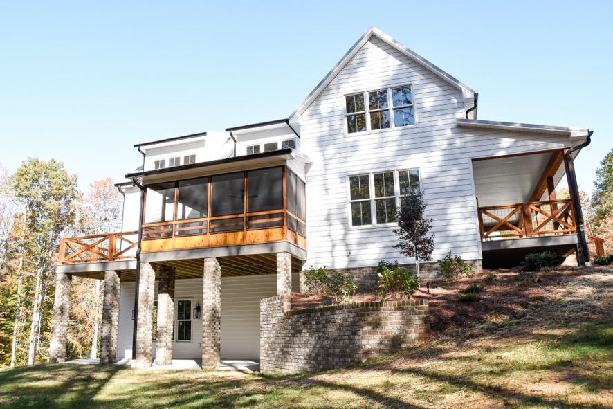 Custom home exterior with white siding, black windows, and wood beam accents by Ryan Noble Construction in North Carolina
